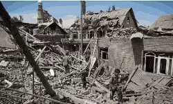 People walk through the rubble of the home of a terrorist that was destroyed at Murran village in Pulwama, South Kashmir,